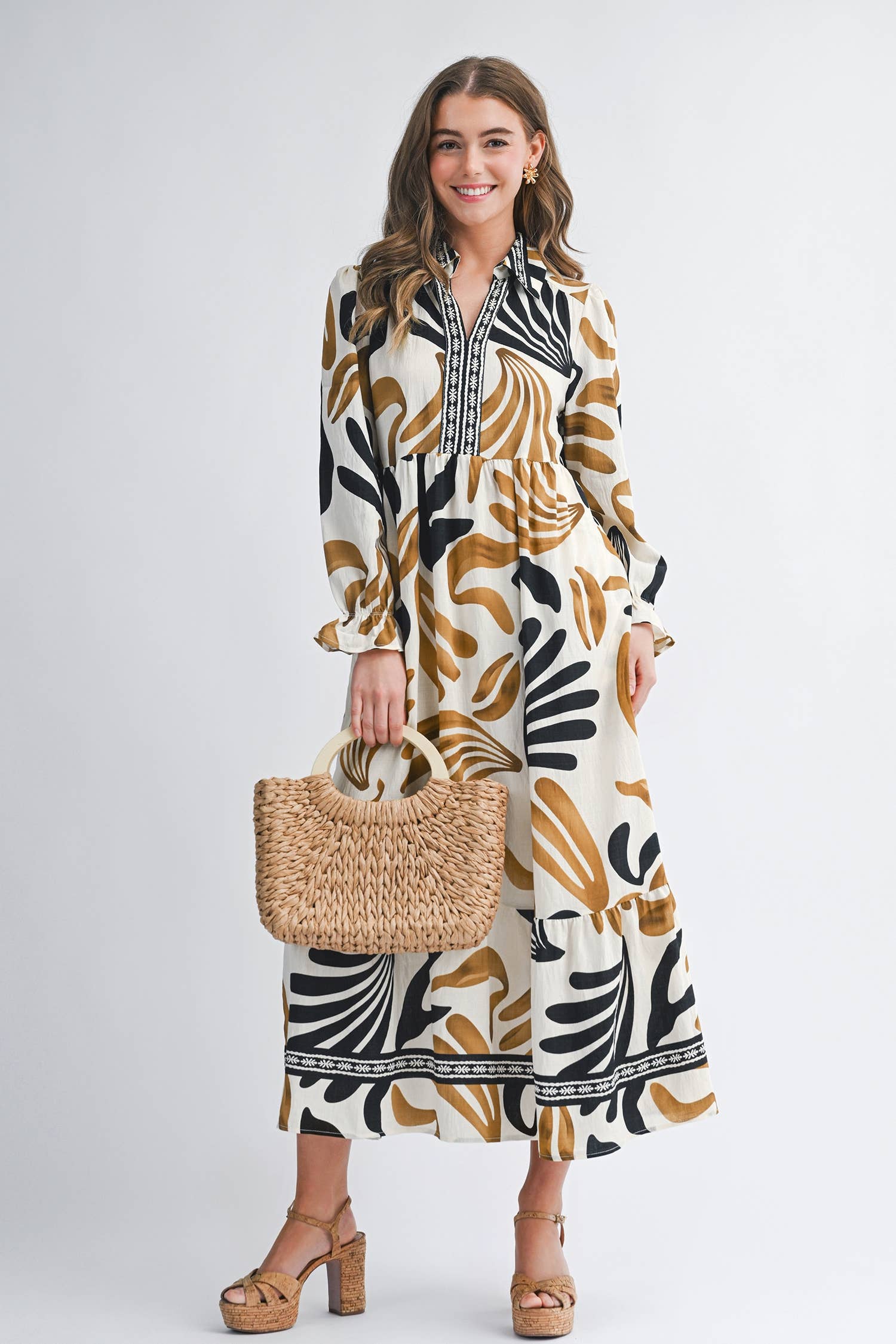 Woman wearing a patterned dress holding a woven bag on a white background