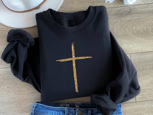 Black sweatshirt with a gold cross on a wooden surface